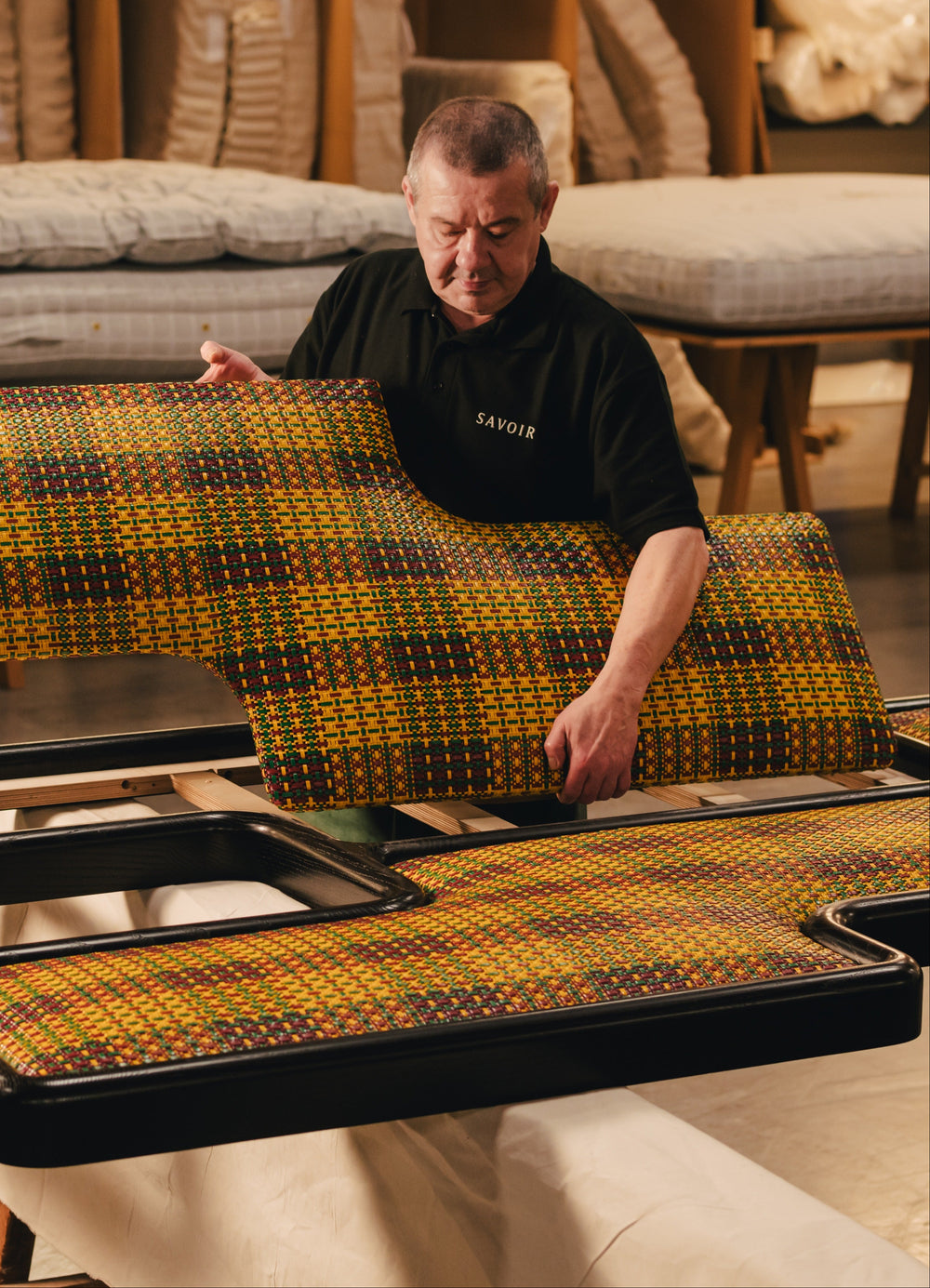 Savoir craftsman with adding the Ozwald Boateng headboard to the wood frame in the workshop